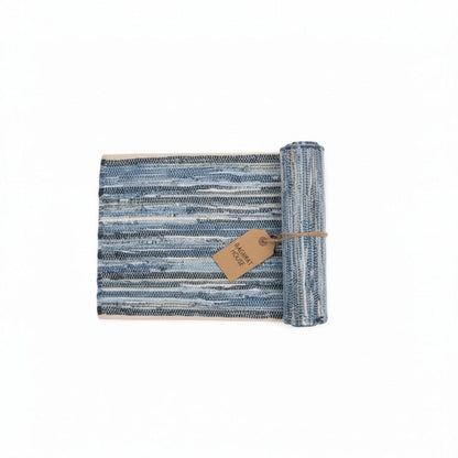 Baghpat House Kirsehir flat-woven jute rug with blue and cream stripes, rolled and tied with twine.