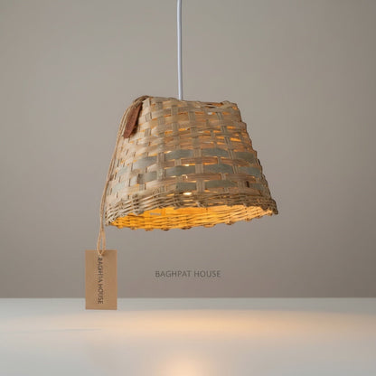 Baghpat House natural woven bamboo pendant light fixture with a tapered shape and artisanal texture, casting a warm glow.